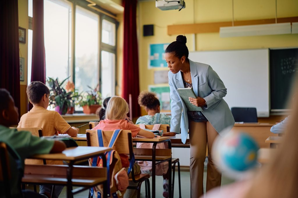 Black teacher assisting her students during a class at elementary school.